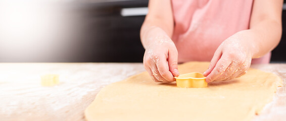 Obraz na płótnie Canvas children's hands prepare cookies with a heart-shaped cookie cutter