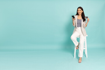 Young Asian businesswoman sitting and showing credit card for making payment in mobile phone...