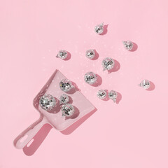 New Year party creative layout with  dico balls christmas decoration in dustpan on pastel pink background. 80s or 90s retro fashion aesthetic concept. New Year celebration idea.