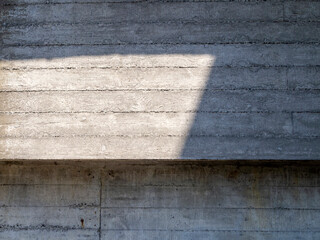 A fragment of a concrete wall with a texture of wood panels on which a shadow falls.