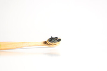 cepillo de dientes de bambú manchado con pasta de dientes negra para blanquear los dientes. Concepto de desperdicio cero.