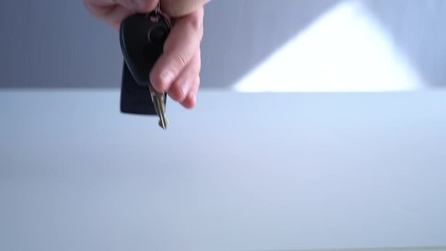 Take the car keys from the table. Male hand takes car keys with remote control