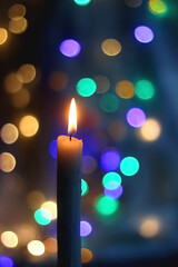 Lit candle and beautiful colorful bokeh lights. Selective focus.