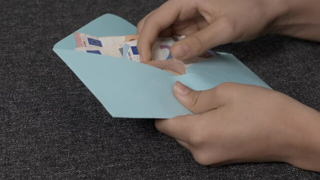Teenage boyd hands open blue envelope, checking, counting cash Euro banknotes. Present gift, saving, financial literacy for children