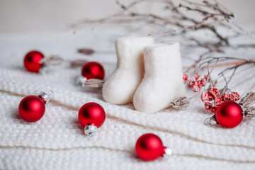 New Year's card: winter national shoes made of handmade wool with branches with frost and red Christmas balls.