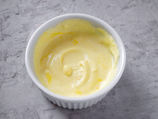 Side view of cheese sauce (coulis de parmesan) in a white bowl. Contains parmesan, cream and saffron.