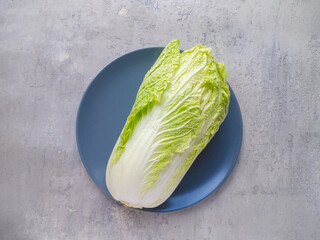 Top view of one raw Chinese cabbage on a blue plate.