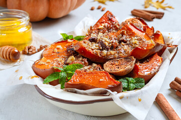Pieces of baked pumpkin with nuts, spices, figs, honey in a bowl. Close-up. Diet, lean menu.