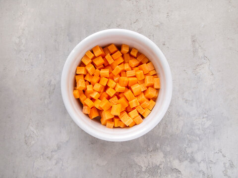 Top view of a white bowl with chopped carrots. Brunoise carrot.