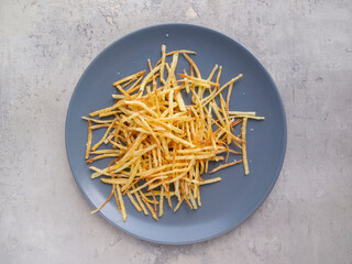 Top view of french fried potatoe straws on a rustic gray concrete background.
