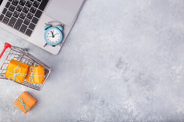 Laptop and orange presents on blue table flat lay. Holiday online shopping concept.