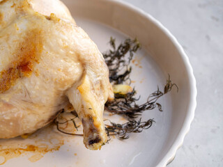 Side view of a portion of baked chicken with garlic and thyme.