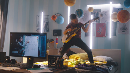 Zoom in view of teen musician playing energetic song on electric guitar while standing on bed near...