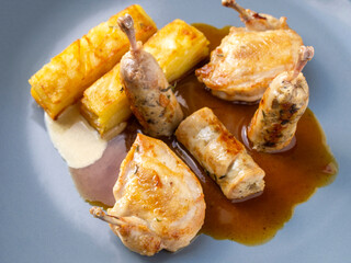 Side view of quail sous vide and potato gratin on a blue plate.