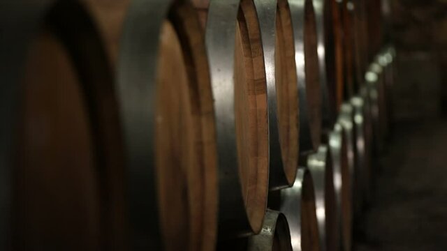 A Wine Cellar. Storage Room for Wine in Bottles and Barrels. Old wine in a dark underground vault. Wooden oak whiskey, wine, cognac, brandy or beer barrels. Bottles on wooden shelves.