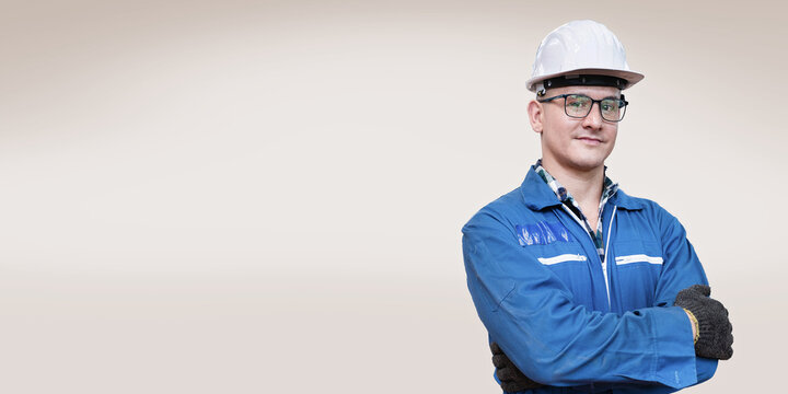 Factory engineer man standing confidence with green working suite dress and safety helmet. manual worker in front grey background. Concept of smart industry worker operating.