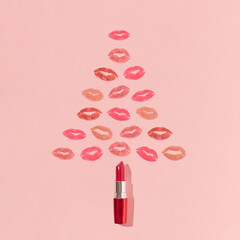 Christmas tree shape made of lipstick and colorful lip prints on bright pink background. Minimal...