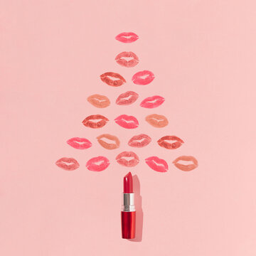 Christmas tree shape made of lipstick and colorful lip prints on bright pink background. Minimal New Year beauty concept. Creative make up or cosmetic aesthetic. Holiday kisses pattern.