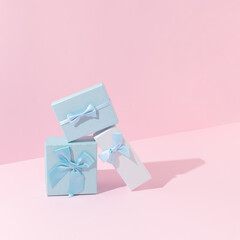 Three pastel blue gift boxes against bright pink background. Minimal Christmas or New Year present concept. Holiday aesthetic.