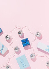 Creative Christmas layout made of blue gift boxes and shiny disco balls on bright pink background. New Year party concept. 80s or 90s retro aesthetic. Holiday flat lay.