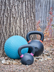 heavy iron kettlebells and slam )or medicine) ball in a backyard - home fitness concept
