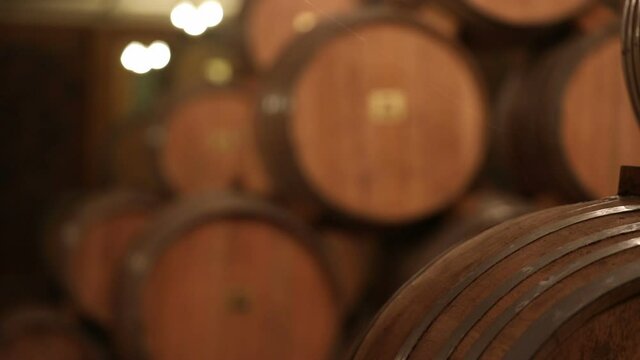 A Wine Cellar. Storage Room for Wine in Bottles and Barrels. Old wine in a dark underground vault. Wooden oak whiskey, wine, cognac, brandy or beer barrels. Bottles on wooden shelves.