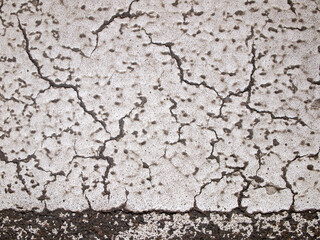 Asphalt in white paint. The surface is damaged and cracked. Abstract background.