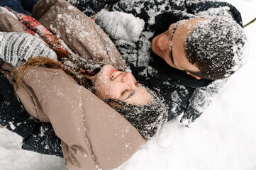 Loving couple in puffer jacket on a winter walk. Man and woman having fun in the frosty forest....
