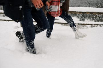 Loving couple in puffer jacket on a winter walk. Mans and womans legs. Romantic date in winter time.Christmas mood of a young family.Winter lovestory