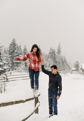 Loving couple in shirt on a winter walk. Man and woman having fun in the frosty forest. Romantic date in winter time.Christmas mood of a young family.Winter lovestory
