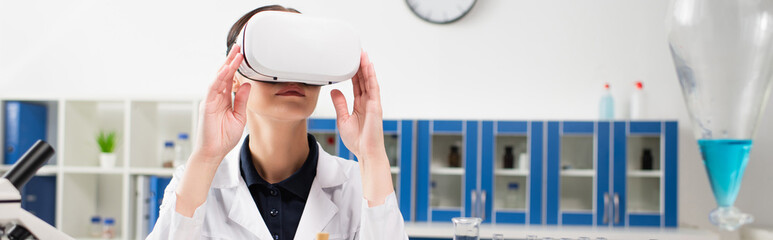 Scientist using vr headset near microscope and flask in lab, banner.