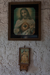 Close up to an antique jesus christ paint with a small holy mary sculpture with white textured wall