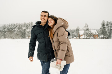 Loving couple in puffer jacket on a winter walk. Man and woman having fun in the frosty forest....