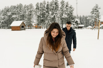 Loving couple in puffer jacket on a winter walk. Man and woman having fun in the frosty forest. Romantic date in winter time.Christmas mood of a young family.Winter lovestory