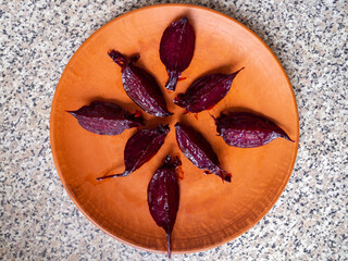 Top view of slices of caramelized beetroot on a brown clay plate.
