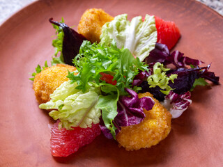 Salad with caramelized beets, grilled goat cheese, peeled grapefruit and lettuce leaves.