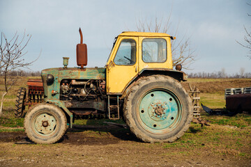 A yellow tractor stands in the countryside. Agriculture and farming.An old tractor.