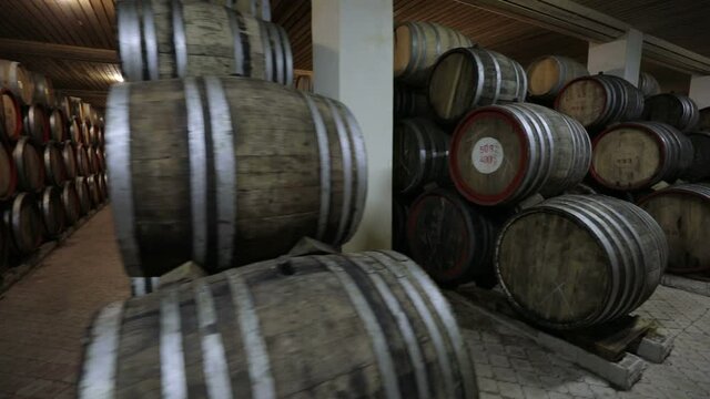 A Wine Cellar. Storage Room for Wine in Bottles and Barrels. Old wine in a dark underground vault. Wooden oak whiskey, wine, cognac, brandy or beer barrels. Bottles on wooden shelves.
