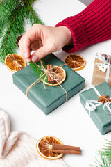 Christmas gift box with female hand and dry oranges decorations over white background