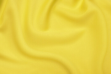 Close-up texture of natural orange or yellow fabric or cloth in same color. Fabric texture of natural cotton, silk or wool, or linen textile material. Yellow canvas background.