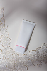 Mock up tube, no brand label and lace on white background with light shadow play. Face skin care cosmetics template