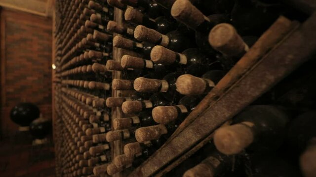 A Wine Cellar. Storage Room for Wine in Bottles and Barrels. Old wine in a dark underground vault. Wooden oak whiskey, wine, cognac, brandy or beer barrels. Bottles on wooden shelves.