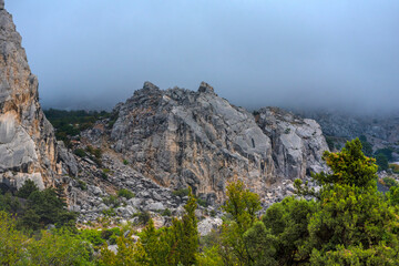 Fototapeta na wymiar Stony slopes of mountain in dense fog.