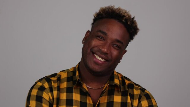 Handsome charismatic young African American man wears a plaid shirt, looks at the camera and smiles. Isolated on a white background studio portrait of a black man. Concept positive emotions of people