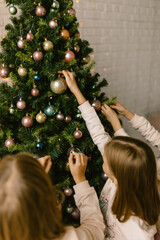 Sisters decorate Christmas tree with Christmas toys
