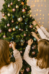 Sisters decorate Christmas tree with Christmas toys