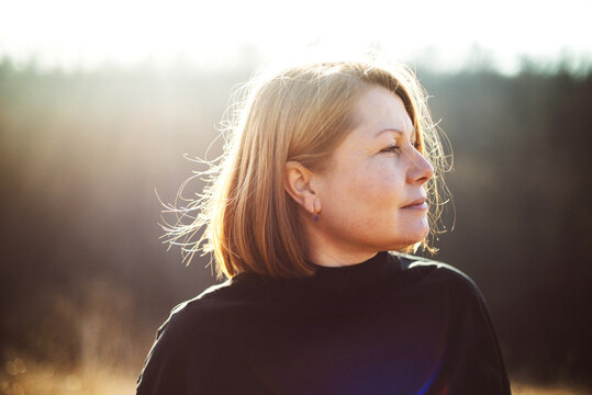 Portrait of adult  woman standing in field  sunset