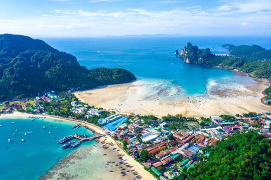 Flying above busy tropical island port filled with boats and fer