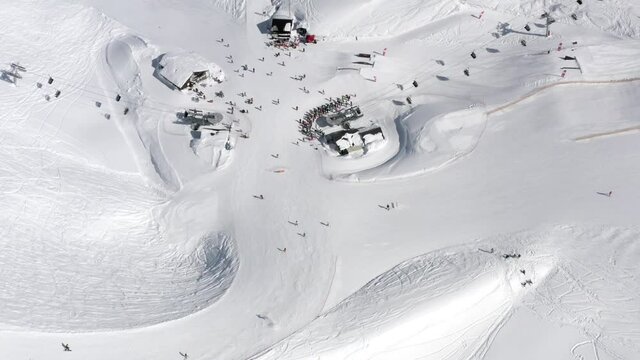 Aerial view mountain ski resort recreational touristic center with riding people. Relaxed active man and woman ride on snowboard, cable car surrounded by snow panorama