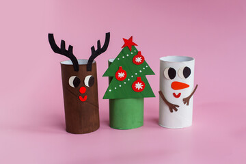 Holiday easy DIY craft idea for kids. Toilet paper roll tube toy Christmas tree, snowman, deer on pink background. Creative New Year and xmas decoration eco-friendly, reuse, recycle handmade concept